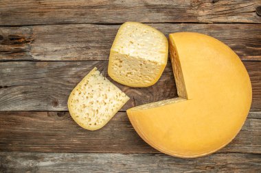 emmental semi-hard cheese with big holes on a wooden background, banner, menu, recipe place for text, top view,