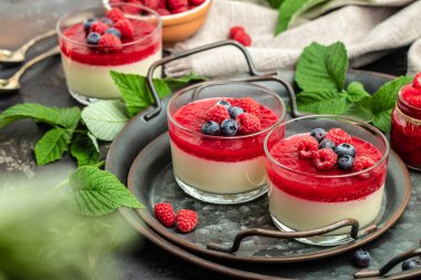 İtalyan tatlısı. Ahudududulu panna cotta, üzerinde ahududu reçeli ve koyu bir arka plan. Küçük kavanozlarda krema soslu böğürtlen tatlısı. Uzun afiş biçimi. metin için yer.