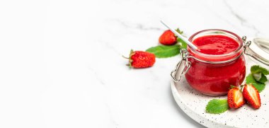 Beyaz arka planda bir kavanoz çilek reçeli. Ev yapımı çilekli marmelat ve meyve. Uzun pankart biçimi.