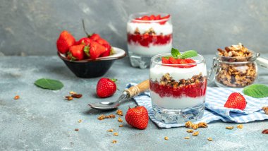 Taze meyve, yoğurt ve beyaz masada granola, cam kavanoz. Sağlıklı kahvaltı. Uzun afiş biçimi. en üstteki görünüm.
