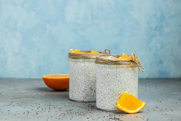 Chia Seed with lactose-free yogurt in glass decorated with citrus fruit. Yogurt with chia seeds on gray background. healthy superfood. Healthy food. vertical image. place for text.