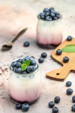 Krem peynirli, kremalı ve kavanozda yabanmersini reçelli yaban mersini tatlısı. dikey görüntü. Üst Manzara. metin için yer.