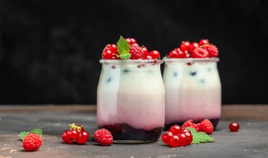 Ahududulu tatlı peynirli kek, ıvır zıvır, bardaktaki fare. Ahudududulu Yunan yoğurdu, koyu arkaplanda granola parfe. Restoran menüsü, diyet, yemek kitabı tarifi..