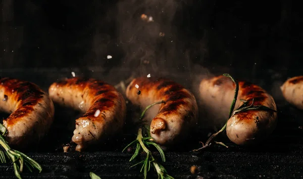 Grilled sausages on grill with smoke and flame on dark background, The concept cooking meat. Food recipe background. Close up. place for text,