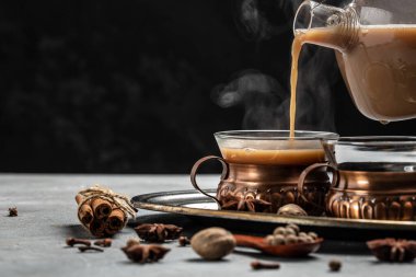 İki kupa Masala çayı. Koyu arkaplanda cam bardakta süt ve baharatlı sıcak Hint masala çayı. metin için yer.