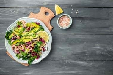 Taze avokado salatası, karides, marul yeşili karışım ve zeytinyağı, limon sosu. Sağlıklı yemek, lezzetli kahvaltı ya da atıştırmalık, temiz yemek, diyet, vejetaryen yemek konsepti. en üstteki görünüm.