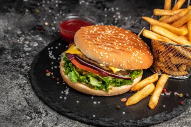 Ev yapımı hamburger, ızgara et, sebze, koyu arkaplanda sos. Fast food ve abur cubur kavramı.
