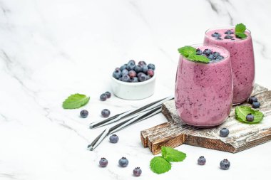 İki bardak taze böğürtlen yoğurtlu meyve suyu taze yaban mersini ya da hafif arkaplanda yaban mersini. Uzun afiş biçimi. en üstteki görünüm.