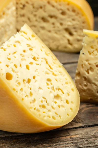 Cheese. French emmental semi-hard cheese with big holes on a wooden background.