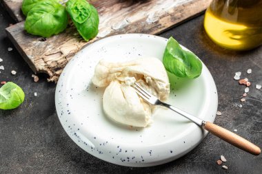 Basil yapraklı burrata peyniri beyaz tabakta koyu arkaplanda. afiş, menü, metin için tarif yeri, üst görünüm.