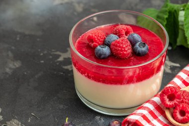 Küçük kavanozlarda koyu arka planda böğürtlen soslu lezzetli İtalyan tatlı panna cotta. metin için yer.