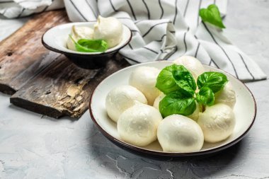Peynir koleksiyonu, beyaz İtalyan peynirli mozzarella topları, arka planda taze fesleğen yapraklarıyla servis edilmiş, yazı için yer, üst manzara.,