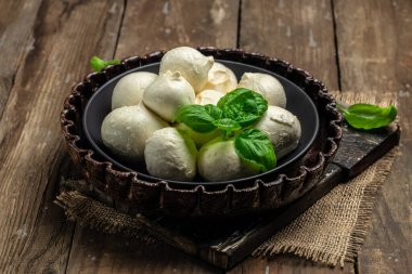 Geleneksel mozzarella peyniri. Koyu ahşap arka planda taze fesleğen yaprakları. afiş, menü, metin için tarif yeri, üst görünüm,