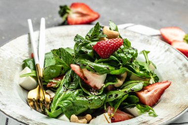 Çilekli taze vejetaryen salatası, ıspanak yaprakları ve gri taş arka planda beyaz peynir, afiş, menü, yazı için tarif yeri, üst görünüm.,