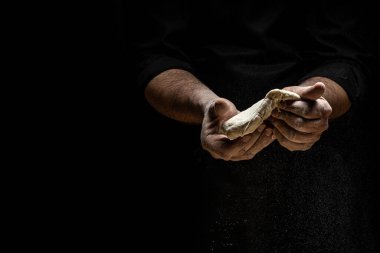 Siyah arka planda izole edilmiş hamur yoğuran fırıncının elleri. Ekolojik olarak doğal hamur işleri hazırlıyor. metin için yer.