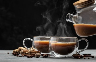 Hint masala çayı. Sıcak masala chai baharatlı çay ve süt ve baharatlar gri arka planda bir cam bardağa dökülür. Uzun afiş biçimi. metin için yer.