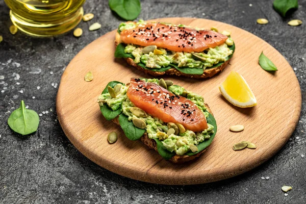 toast with avocadoo, salmon and spinach, nuts, sunflower seeds. Healthy, clean eating. Vegan or gluten free diet. top view, copy space.