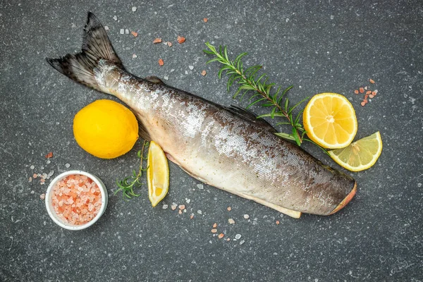 Salmon fish or raw rainbow trout on a dark background. Simple seafood recipe. place for text, top view.