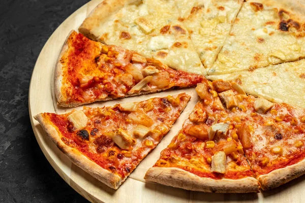 Tasty hawaiian pizza with chicken and pineapple pizza Four Cheeses on wooden cutting board on a dark background. food delivery, place for text, top view.