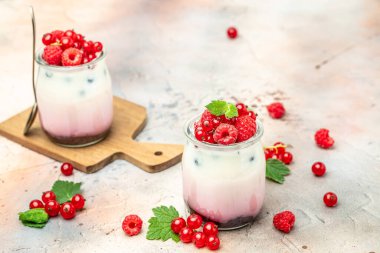 Raspberry dessert cheesecake, trifle, mouse in a glass. Raspberry Greek yogurt granola parfait on a light background. Restaurant menu, dieting, cookbook recipe.