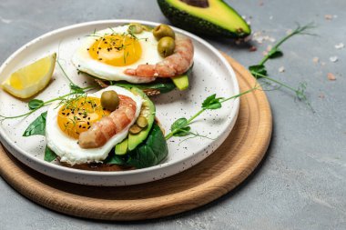 Tost ekmeği, yağda yumurta, ıspanak, avokado, gri arka planda karides, ketogenik kahvaltı. Süper yiyecek konsepti. Sağlıklı, temiz yemek. Üst görünüm.