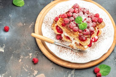 Yaz tatlısı, nane yapraklarıyla süslenmiş ahududulu klasik tiramisu. dikey görüntü. en üstteki görünüm.