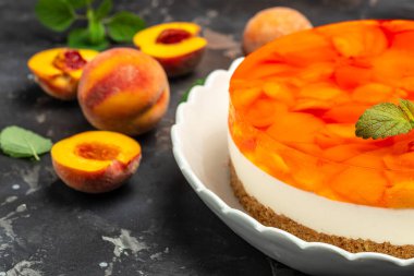 Tasty cheesecake with fruit peaches, peache jelly, jam on a dark background.