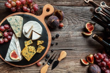 Çeşitli peynir çeşitleri, geleneksel Fransız parçaları, İtalyan ve İspanyol manchego peyniri üzümlü ve incirli ahşap masada servis edilmiş..