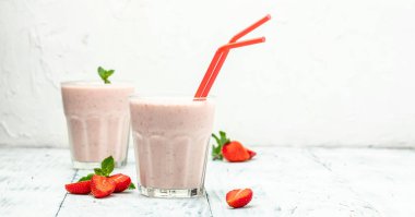 Strawberry smoothie or milkshake with berries and yogurt in glass jar on white concrete background. Vegetarian healthy drink. place for text, top view,