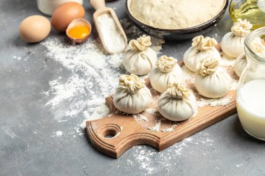 Etle çiğ Khinkali, tahtadan bir tahta üzerinde un, yarı bitmiş ürünler khinkali pişiriyor. Gürcistan hamur tatlısı.