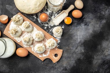 Etle çiğ Khinkali, tahtadan bir tahta üzerinde un, yarı bitmiş ürünler khinkali pişiriyor. Gürcistan hamur tatlısı.
