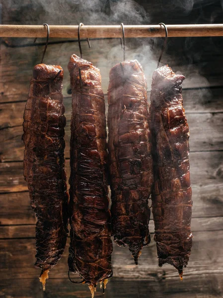 Traditional method of smoking meat in smoke. Smoked ham, bacon, pork neck and sausages in a smokehouse.