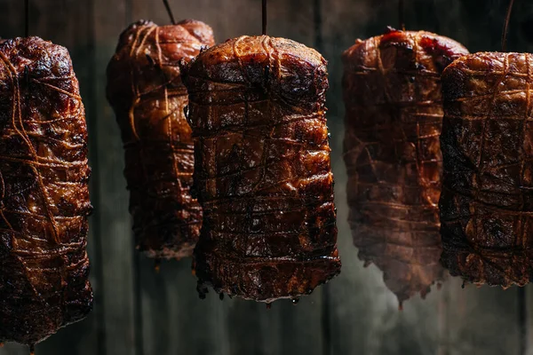 Traditional method of smoking meat in smoke. Smoked ham, bacon, pork neck and sausages in a smokehouse.