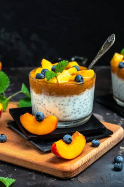 yogurt dessert with peaches blueberry chia on a dark background. Natural detox, fruit dessert, healthy dieting concept.