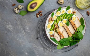 Salata avokado, ızgara tavuk fileto, bıldırcın yumurtası, ıspanak, fındık. Keto diyeti. Sağlıklı yağlar, kilo vermek için temiz yiyecekler, uzun afiş formatı. en üstteki görünüm.