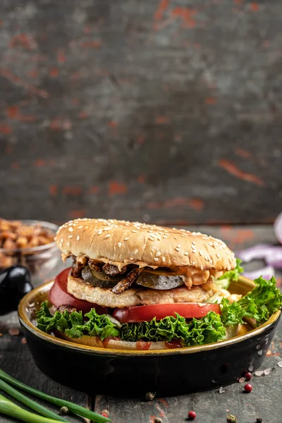 Homemade burger with grilled meat, vegetables, sauce on rustic wooden background. fast food and junk food concept.