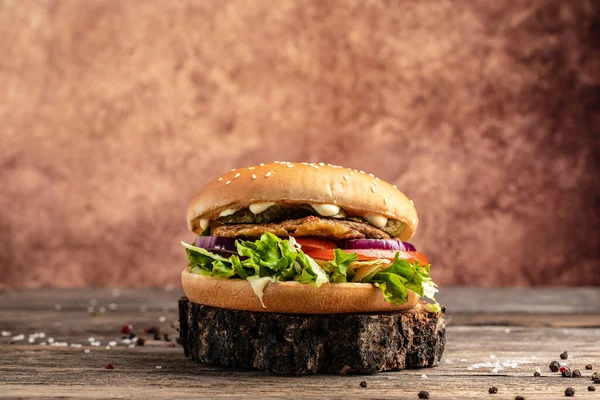 homemade burger with grilled meat, vegetables, sauce on rustic wooden background. fast food and junk food concept,