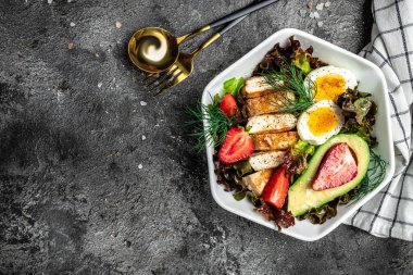 Ketojenik düşük karbonhidrat diyeti. Keto yiyecekli tabak: iki yumurta, avokado, ızgara tavuk fileto, fındık, çilek ve taze salata. Sağlıklı yağlar, kilo vermek için temiz yiyecekler. görünüm.