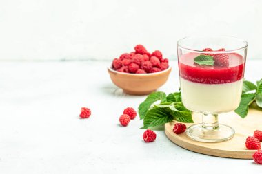 Küçük kavanozlarda krema soslu böğürtlen tatlısı. İtalyan tatlısı. Hafif arka planda ahududu reçelli ahududu panna cotta. metin için yer, üst görünüm.