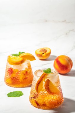 homemade peach sangria with ice cubes, and mint, Refreshing summer homemade cocktails, on a light background, vertical image. top view. place for text,