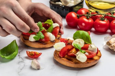 Kadın elleri mutfakta Caprese Bruschetta 'yı hazırlıyor. Lezzetli kahvaltı ya da atıştırmalık, temiz yemek, diyet, vejetaryen yemek konsepti. en üstteki görünüm.
