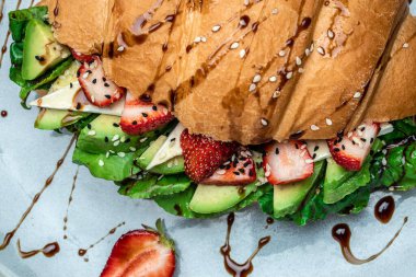 Avokado, çilek, peynirli peynirli sandviç, tohumlu buğday ekmekli taze salata. Sağlıklı beslenme konsepti. afiş, menü, tarif, üst görünüm.