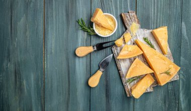Parmesan peyniri dilimlenmiş ve rendelenmiş. Tahta arka planda bıçaklı bir parmesan peyniri seti. Uzun afiş biçimi. en üstteki görünüm.