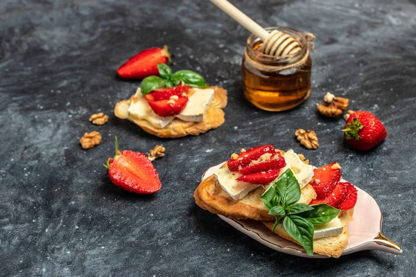 Two toasts or bruschetta with strawberries, cheese camembert nuts and honey. Summer breakfast. Healthy, clean eating. Vegan or gluten free diet.