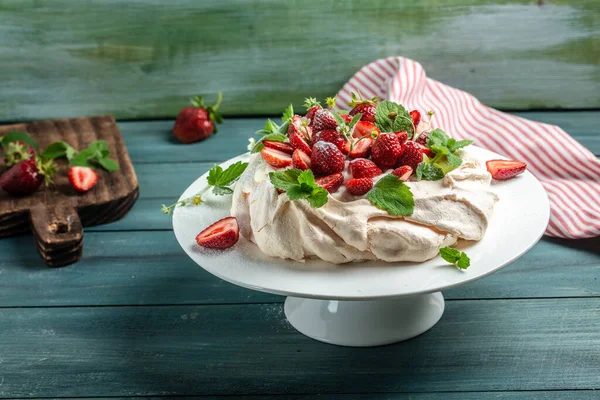 meringue cake Pavlova with whipped cream, fresh strawberries on wooden background, place for text, top view.