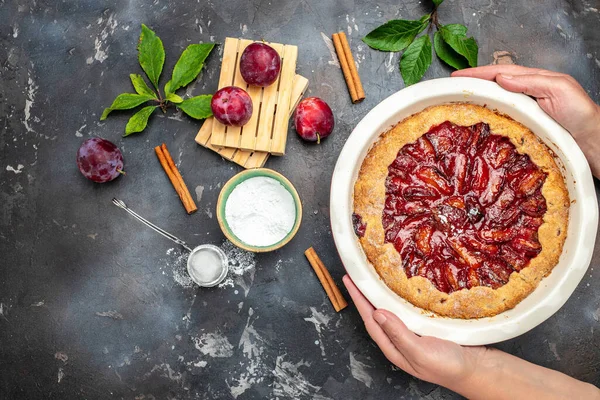 Woman hands holds plum pie. Culinary, cooking, bakery concept. place for text, top view.
