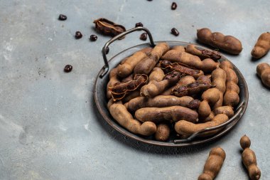 Hafif arka planda sepetin üzerinde nefis olgun tamarindler, egzotik meyveler. afiş, menü, metin için tarif yeri, üst görünüm.