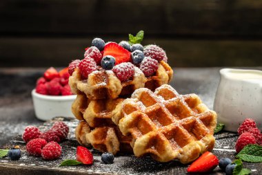Belgian Waffles sweet desert with raspberries, strawberries and blueberries, sugar powder.