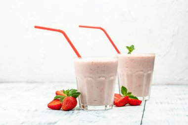 Two glasses of Strawberry smoothie or milkshake with berries and yogurt on white background. Vegetarian healthy drink. place for text,
