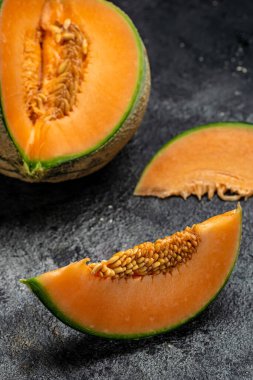 Tam ve dilimlenmiş Japon kavunları ya da koyu arkaplanda kavun. dikey görüntü. metin için yer.
